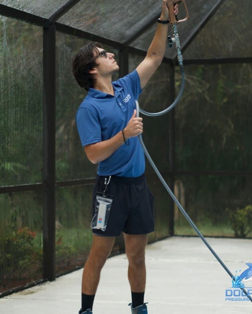 Dolphin Pressure Washing crew soft washing the inside of a pool cage in Naples