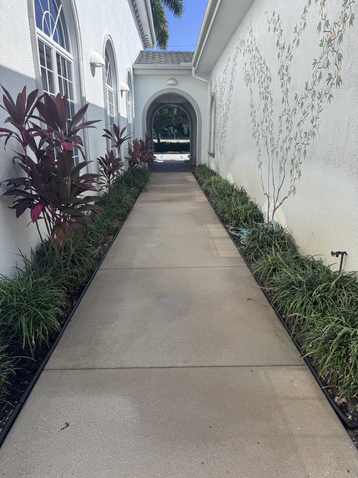 Clean concrete walkway between stucco walls after pressure washing in Naples